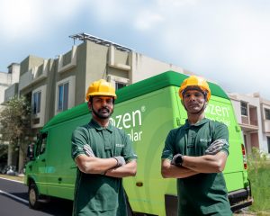 Ecozen engineers posting in front of a tempo van branded with ecozen rooftop solar. Parked in front of a multi storey residential building in India with rooftop solar visible